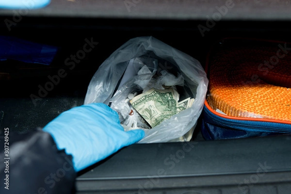 Obraz police finds a bag of money and drugs in the trunk of a detainee