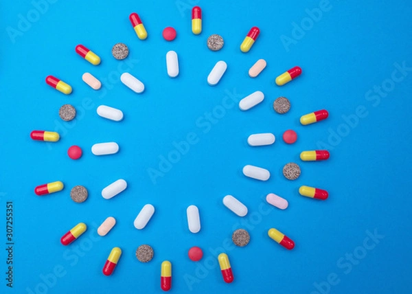 Obraz Group of different pills arranged in shape of circle on blue background