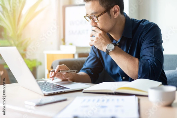 Fototapeta hand holding using texting cell phone and typing computer.businessman at workplace Thinking investment plan.chatting contact Investor.searching for information use internet.connecting people concept