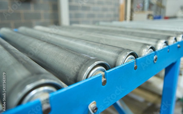 Fototapeta Pusty przemysłowy przenośnik rolkowy w całkowicie zautomatyzowanej fabryce. przenośnik rolkowy do łatwego przenoszenia ciężkich towarów przemysłowych bez udziału ludzi. przyszłość produkcji przemysłowej.