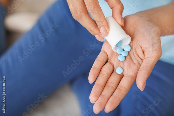 Fototapeta Young woman with pills at home, closeup