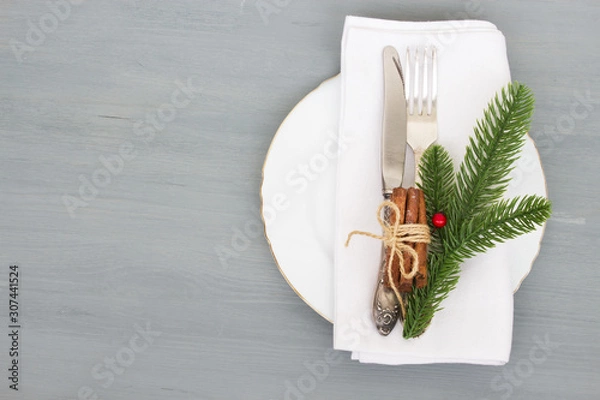 Fototapeta Festive table setting for Christmas dinner on a gray wooden background with place for text. The concept of winter holidays. Flat layout.