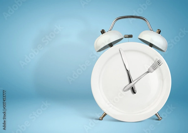 Fototapeta Concept of intermittent fasting, lunchtime, diet and weight loss. Plate as Alarm clock on blue