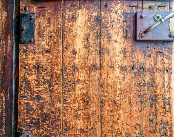 Fototapeta Closeup fragment of a beautiful antique door with a rusty padlock and hinges. Old textured antique doors. Vintage background.