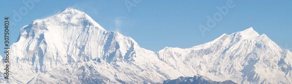 Fototapeta Amazing autumn panorama with mountains covered with snow and forest against the background of blue sky and clouds. Mount Everest, Nepal.