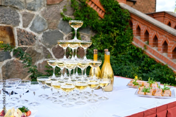 Fototapeta Champagne glass pyramid. Pyramid of glasses of wine, champagne, tower of champagne on wedding party.  For festive reception at the wedding on table