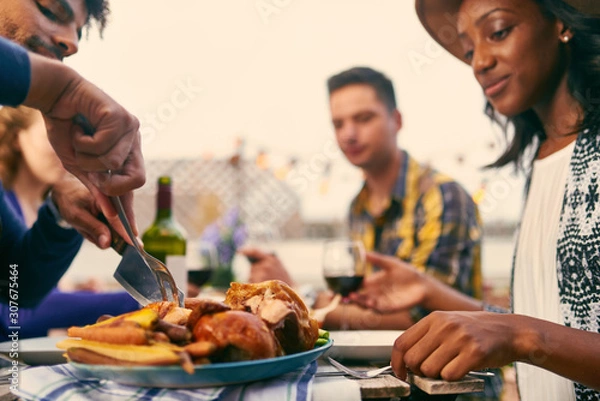 Obraz Group of diverse friends having dinner al fresco in urban settin