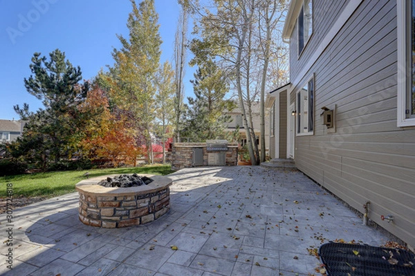 Obraz Back stone patio with fall trees and round stone firepit