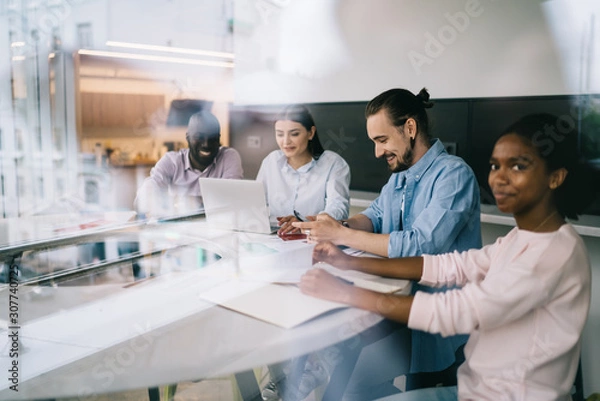 Fototapeta Smiling coworkers sitting table in office space