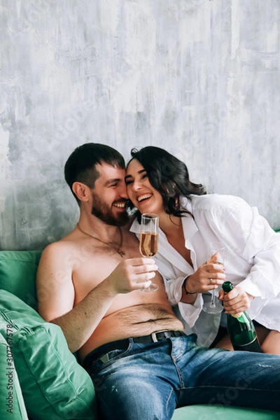 Obraz couple celebrating new year, green sofa, laughing, sparkling wine