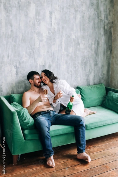 Obraz couple celebrating new year, green sofa, laughing, sparkling wine