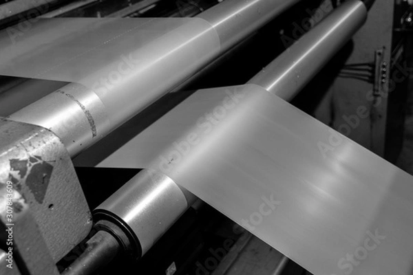 Obraz Black & White imagery of spool of plastic packaging sheet heavy duty for industrial use outdoors. wrapped around a metal pole ready to feed into a machine for cutting into shape or printing logos.