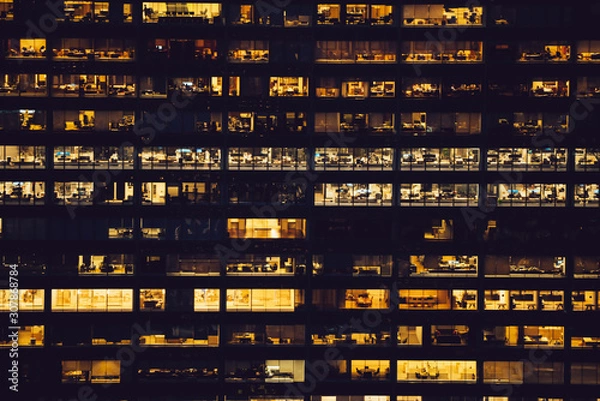 Fototapeta Aerial view of various high Manhattan skyscrapers buildings with lighted windows located in New York city at evening time. Night life of metropolis, offices and real estate. Downtown structures