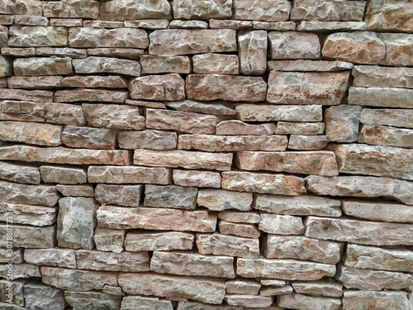 Fototapeta Modern retro style round rock stone uneven wall background on a wall of the building in the outdoors with rough texture and pattern