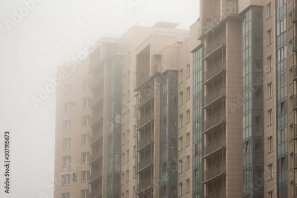 Fototapeta Part of a multistory building in the morning mist. Contemporary typical dwelling.