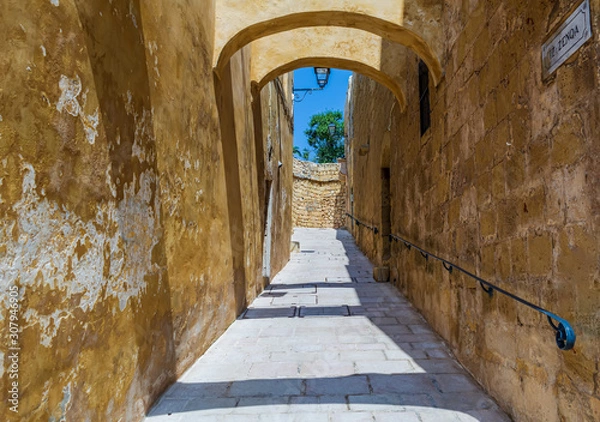 Fototapeta Narrow street with limestone walls in the Cittadella of Victoria in Gozo, Malta.