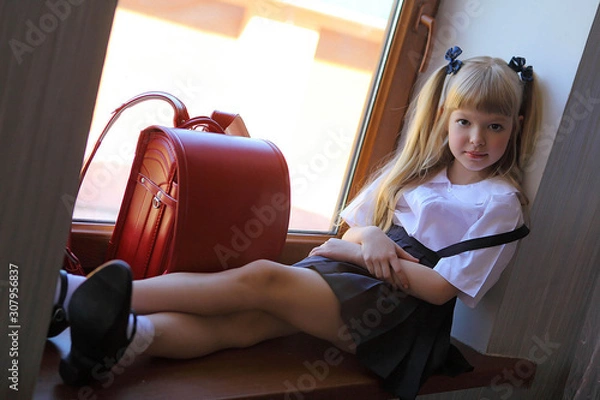 Fototapeta little schoolgirl in a school uniform and a backpack