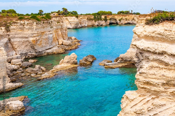 Fototapeta Torre Sant Andrea beach with its soft calcareous rocks and cliffs, sea stacks, small coves and the jagged coast landscape. Crystal clear water shape white stone create natural stacks. Melendugno Italy