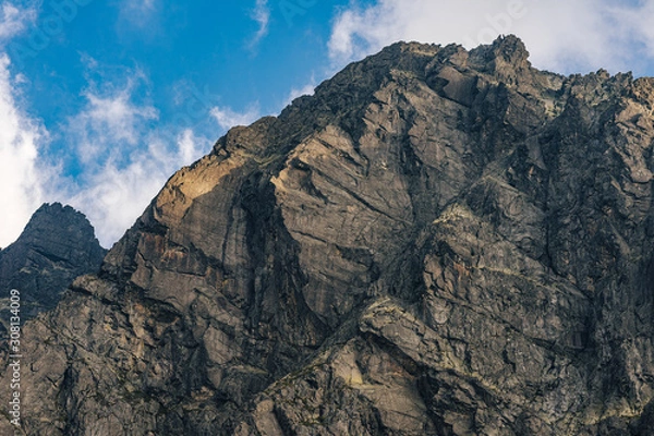 Fototapeta Detail of a mountain rock face, background or wallpaper picture of big wall rock climb, clouds and mist, stone and rock surface. Huge rock wall of granite in High Tatras, Slovakia.