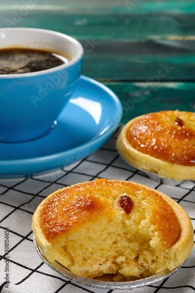 Fototapeta side view fresh cocknut tart with a bite and cup of coffee on back vertical composition
