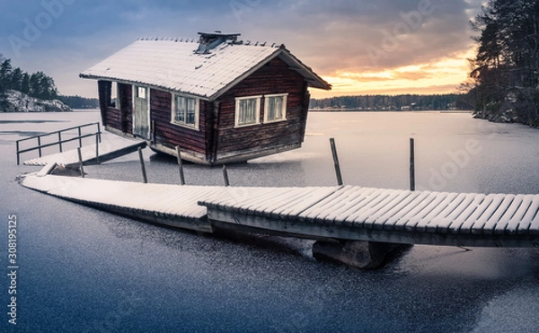 Fototapeta Abandoned sauna and broken pier with sunset landscape at winter evening in Finland
