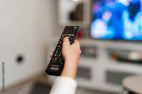 Fototapeta Watching tv on the sofa using remote controller