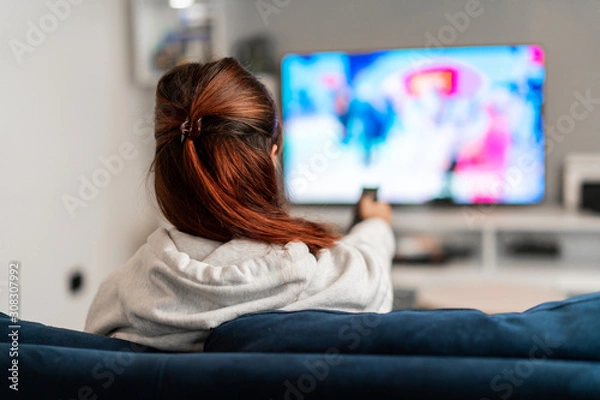 Obraz Dziewczyna ogląda programy telewizyjne na kanapie