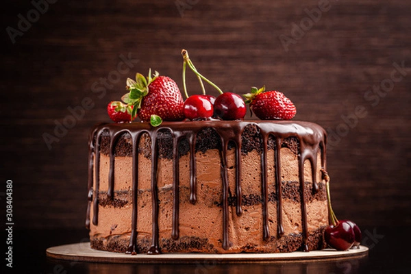 Obraz Chocolate cake with with berries, strawberries and cherries. cake on a dark brown background. copy space
