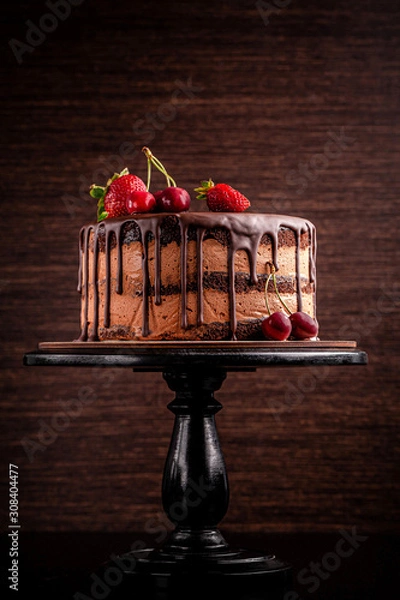 Obraz Chocolate cake with with berries, strawberries and cherries. cake on a dark brown background. copy space