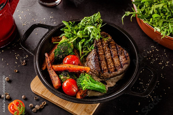 Obraz American food concept. Grilled beef steak with grilled vegetables, with carrots, cherry tomatoes, broccoli, in a cast iron pan. copy space