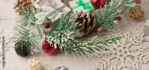 Fototapeta Christmas light gray background on whitewashed wooden boards with green spruce wreath, toys, silver snowflakes and gifts