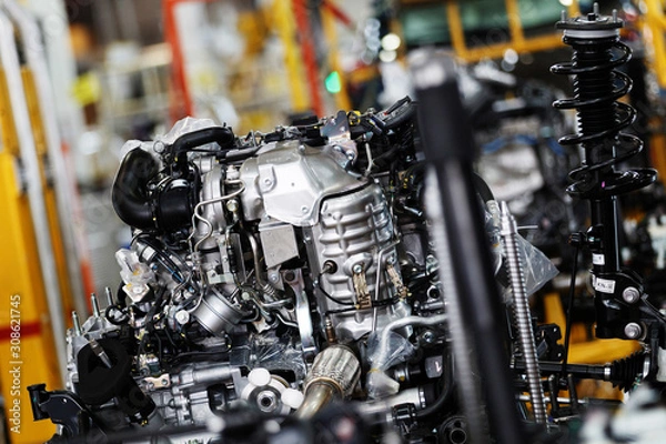 Fototapeta Car factory. An automobile internal combustion engine stands on the conveyor line of the production hall of an automobile plant.
