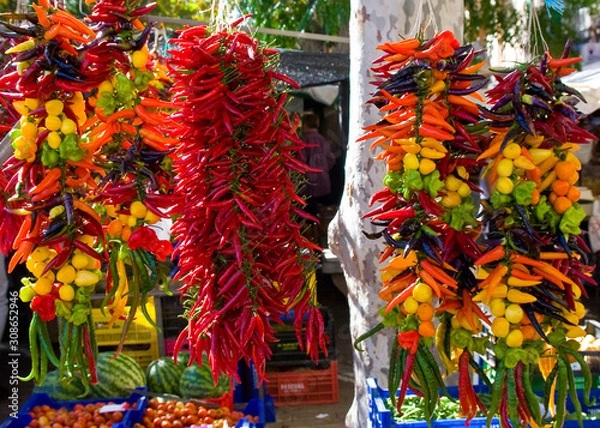 Fototapeta Hanging strings of mixed hot chili peppers for sale at Sineu market, Majorca, Spain