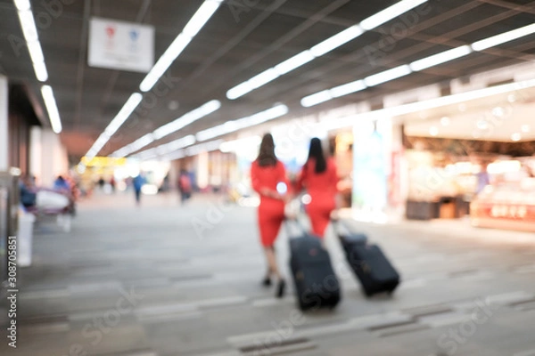 Fototapeta Abstract blur and defocused air hostess with suitcases walking in passenger terminal in the airport