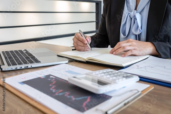 Fototapeta Businesswoman working and planning in investment trading marketing project and using calculator to analyzing data graph of deal a stock exchange to financial business profit
