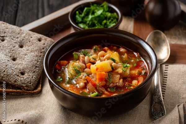 Obraz White bean soup with bacon, on wooden tray. 