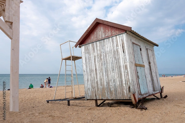 Obraz The empty beach on the sea in autumn with a small abandoned cloakroom. Cloudy sky in the afternoon