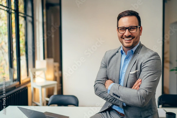 Obraz Portrait of young businessman standing in his office with arms crossed