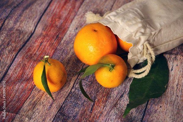Obraz fresh tangerines in organic fabric package isolated on wooden background