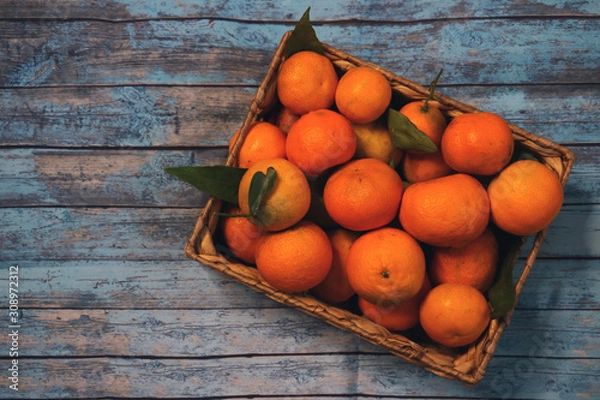 Fototapeta wooden basket with tangerines isolated on background