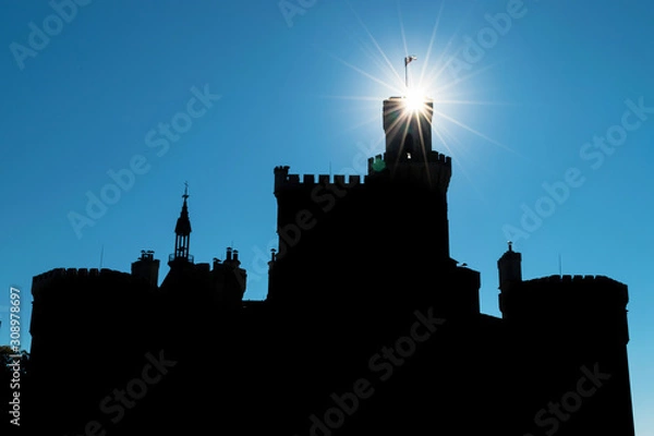 Fototapeta Silhouette of an ancient Hluboka castle with towers on a background of sky with sunbeams Hlubo