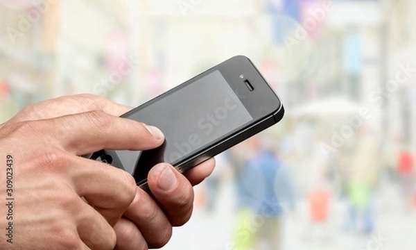 Fototapeta Hand holding smartphone on blurred bokeh background