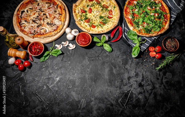 Fototapeta Traditional Italian pizza, vegetables, ingredients on a dark background. Top view with copy space. Pizza menu