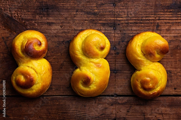 Obraz Swedish traditional christmas bun Lussekatter or Lussebullar on a rustic wooden table background