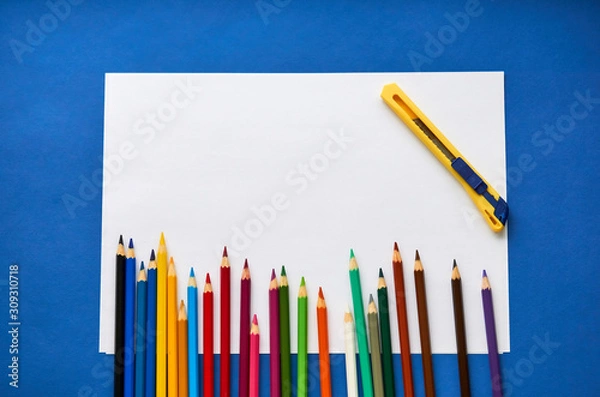 Fototapeta Color pencils and white sheet of paper on a blue background