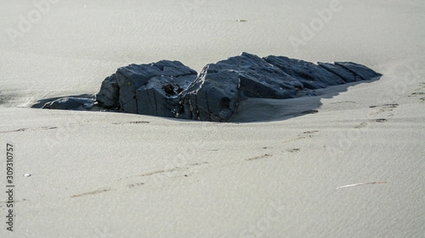Fototapeta Rock boulder revealed by waves beach sand .