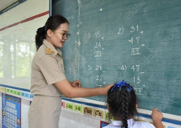Fototapeta Thai female teacher are teaching mathematics to elementary school students in classroom, The message posted at the bottom of the chalkboard is an educational material that is vowels in Thai Language