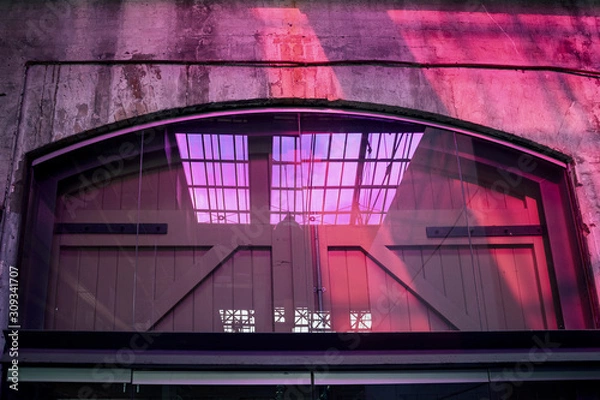 Fototapeta Purple light reflecting on the wall and a big door