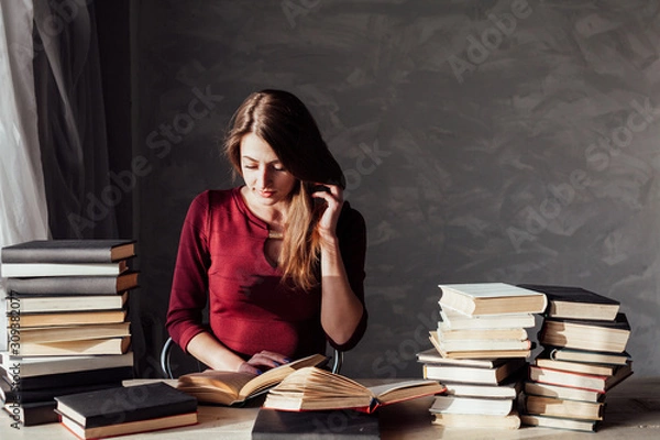 Fototapeta girl reading a book in the library is preparing for the exam