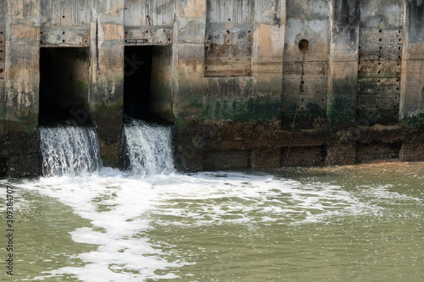 Fototapeta dirty water flow to sewer from city, waste water flows from a pipe, Sewage pipe polluting water